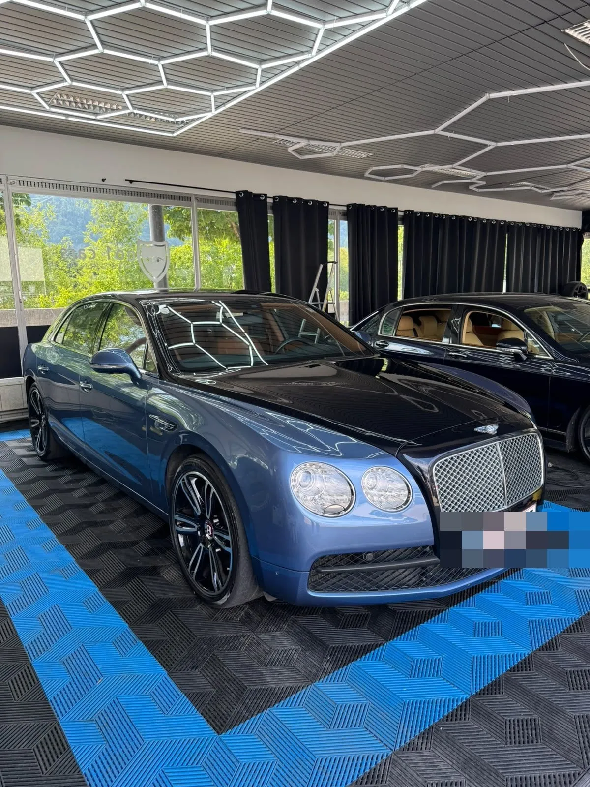 Bentley Flying Spur in der Halle von Saff Car Lounge in Kufstein nach der Aufbereitung, Hexagon-Leuchten spiegeln sich im Lack