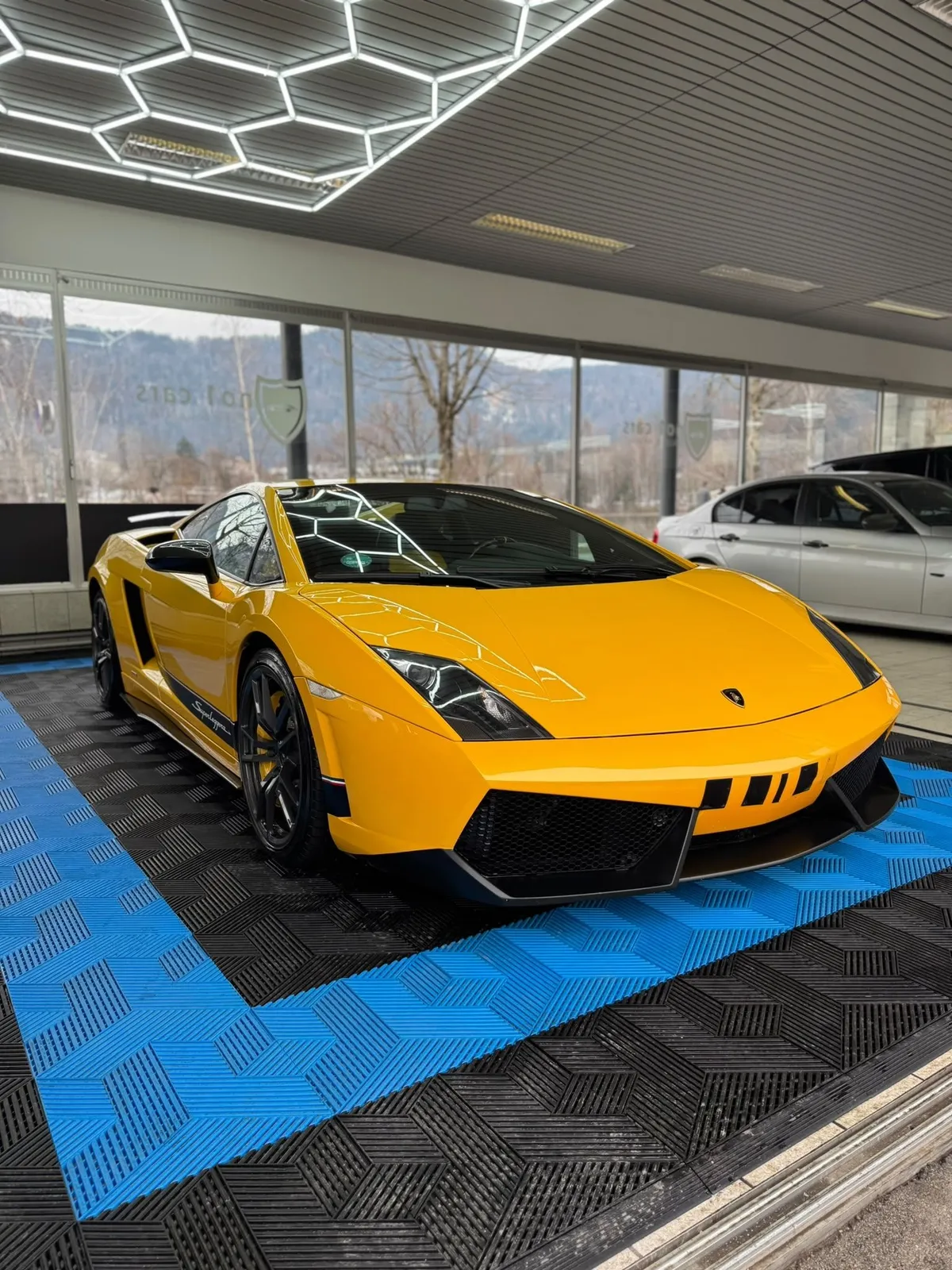 Gelber Lamborghini Gallardo auf dem gerasterten Hallenboden mit blauen Streifen
