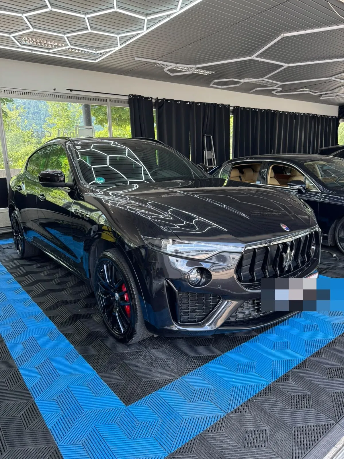 Maserati Levante in der Halle von Saff Car Lounge in Kufstein nach der Aufbereitung, Hexagon-Leuchten spiegeln sich im Lack