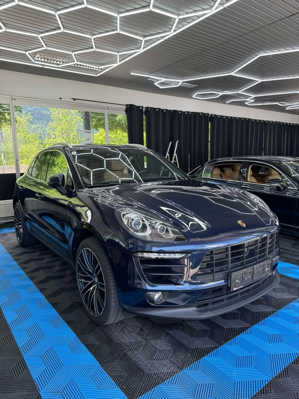Porsche Macan in der Halle von Saff Car Lounge in Kufstein nach der Aufbereitung, Hexagon-Leuchten spiegeln sich im Lack