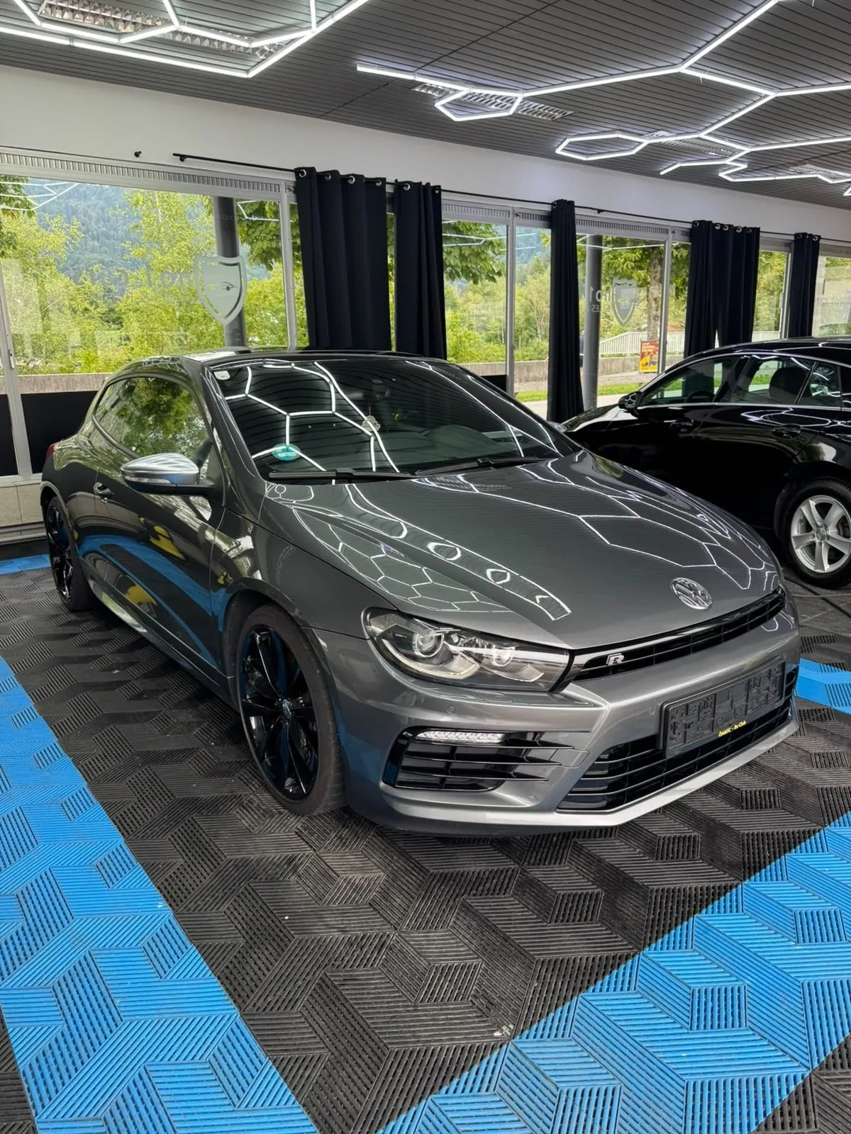 VW Scirocco R in der Halle von Saff Car Lounge in Kufstein nach der Aufbereitung, Hexagon-Leuchten spiegeln sich im Lack