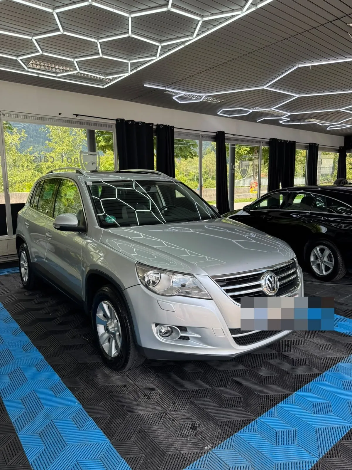 VW Tiguan in der Halle von Saff Car Lounge in Kufstein nach der Aufbereitung, Hexagon-Leuchten spiegeln sich im Lack